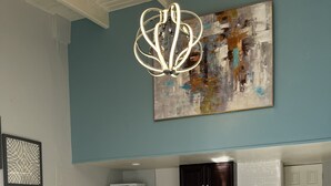 Une chambre avec un lit, une kitchenette équipée d’une cuisinière et d’un four à micro-ondes, et un luminaire fixé au plafond.