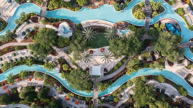 Ein Luftbild eines Resorts mit mehreren Swimmingpools, Liegebereichen und üppiger Bepflanzung.