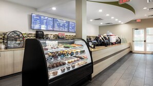 Eine Bäckereiauslage mit verschiedenen Backwaren, einer Kaffeemaschine und einer digitalen Speisekarte.