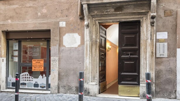 A building entrance with a sign indicating new opening hours and a luggage deposit service. - Aurora in Pantheon Apartment (Rome)