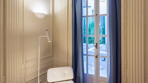 A room with a white chair, a floor lamp, and a door with blue curtains. - Queen Suite By 33Solonos Suites (Athina)