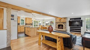 Une cuisine moderne avec des meubles en bois, un îlot central et une cheminée en pierre.