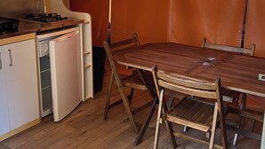 Una cocina compacta con estufa a gas, un refrigerador pequeño y una mesa de comedor con sillas.