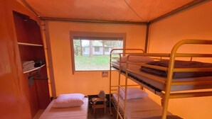 Una habitación tipo dormitorio con literas, una ventana, una mesita y un armario.