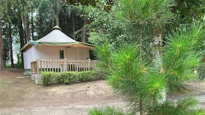 Una cabaña pequeña con un porche, rodeada de un bosque denso.