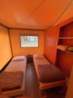 A compact room with two single beds, a small window, and a closet with hanging space.