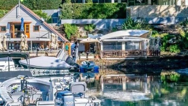 Un puerto deportivo con barcos amarrados, una casa con balcón y un edificio con zona cubierta.