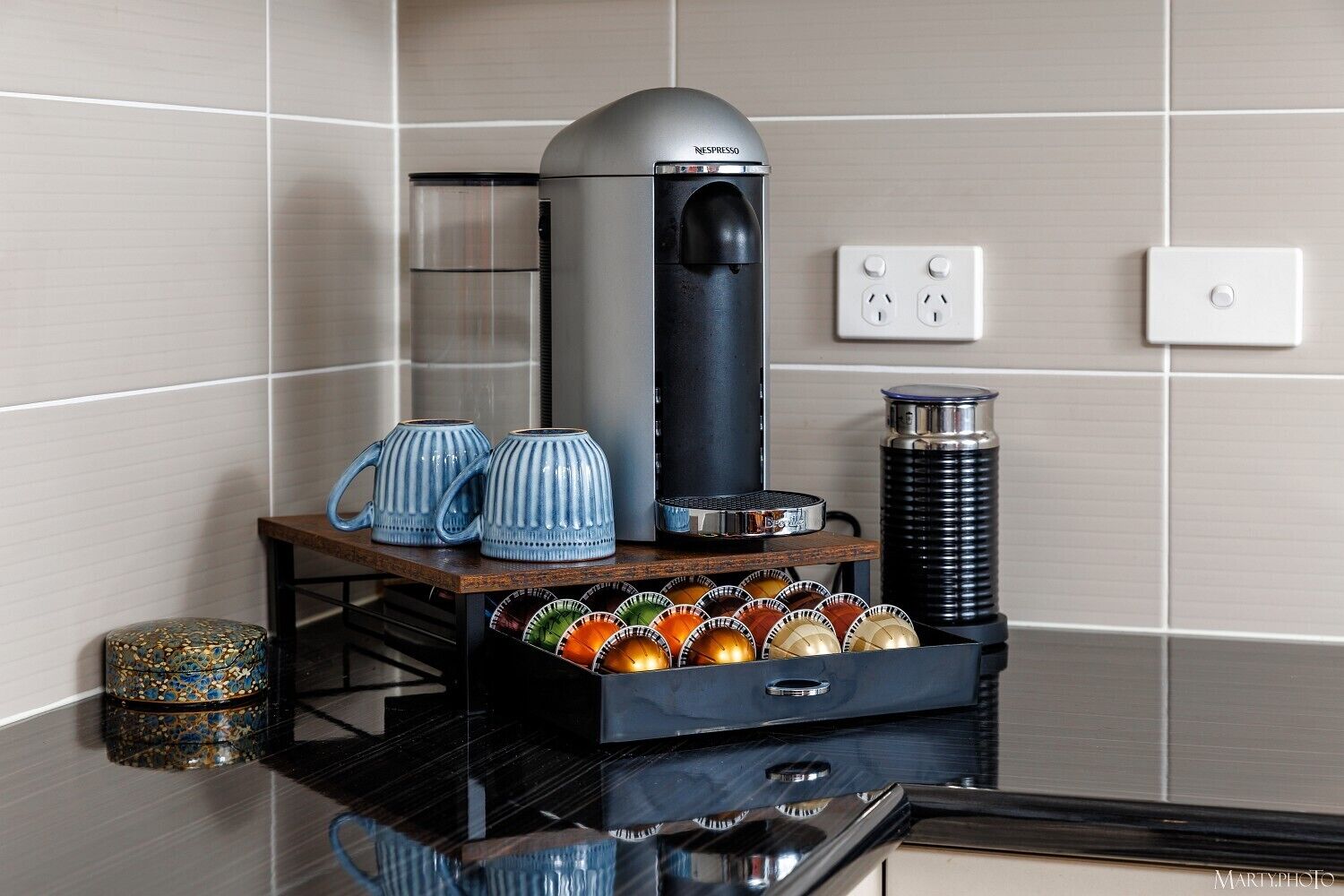Een keuken met een Nespresso koffiemachine, een koffiemolen en een houder voor koffiecups.
