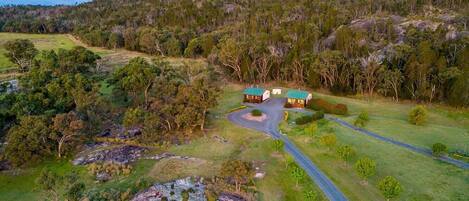 A rural landscape with a winding road leading to a cluster of buildings with green roofs.