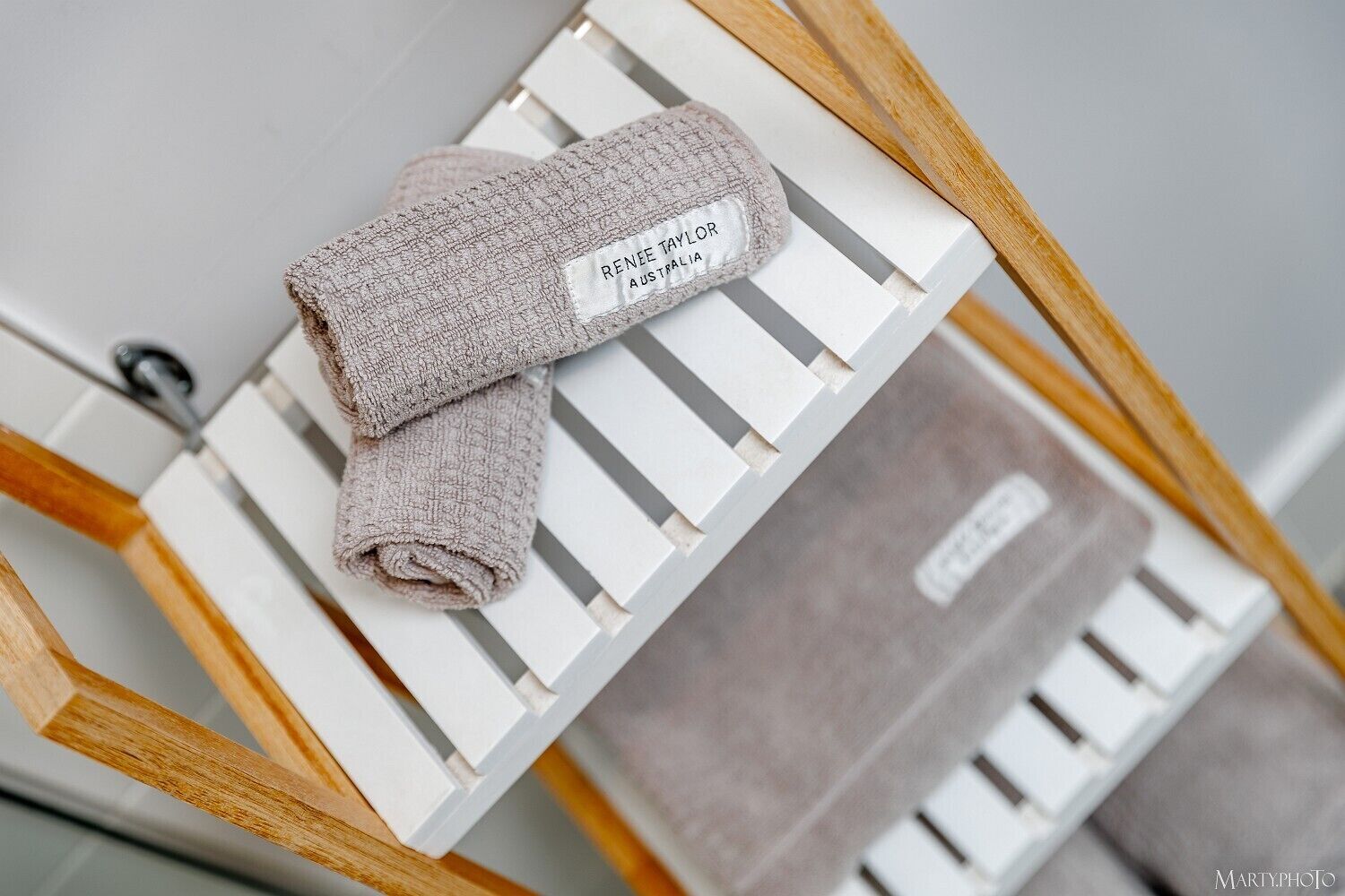 A neatly folded towel with a label on a white wooden stand.