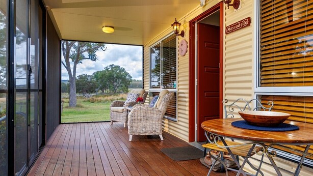 A wooden deck with wicker furniture and a table with a bowl. - Stargazers Escape Stanthorpe (Diamondvale)