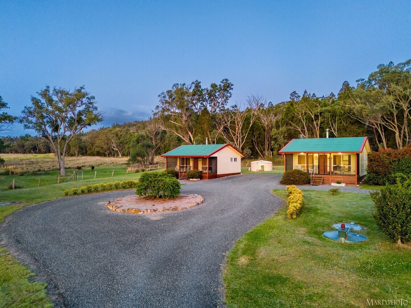 A property with two cabins, a gravel driveway, and a well-maintained lawn.