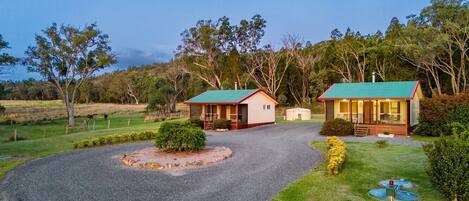 A property with two cabins, a gravel driveway, and a well-maintained lawn.