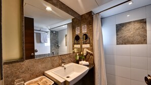 Baño con lavamanos grande, espejo y cortina de ducha.