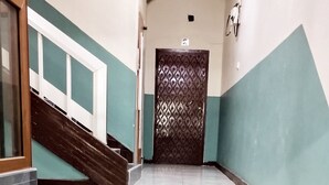 Un escalier dont les marches alternent entre le blanc et le gris, menant à une porte ornée d’un motif décoratif.