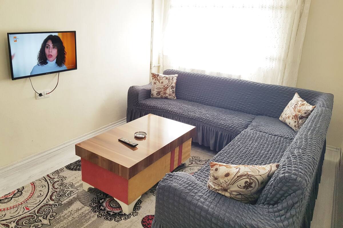 Un salon avec un canapé, une table basse et un téléviseur fixé au mur.