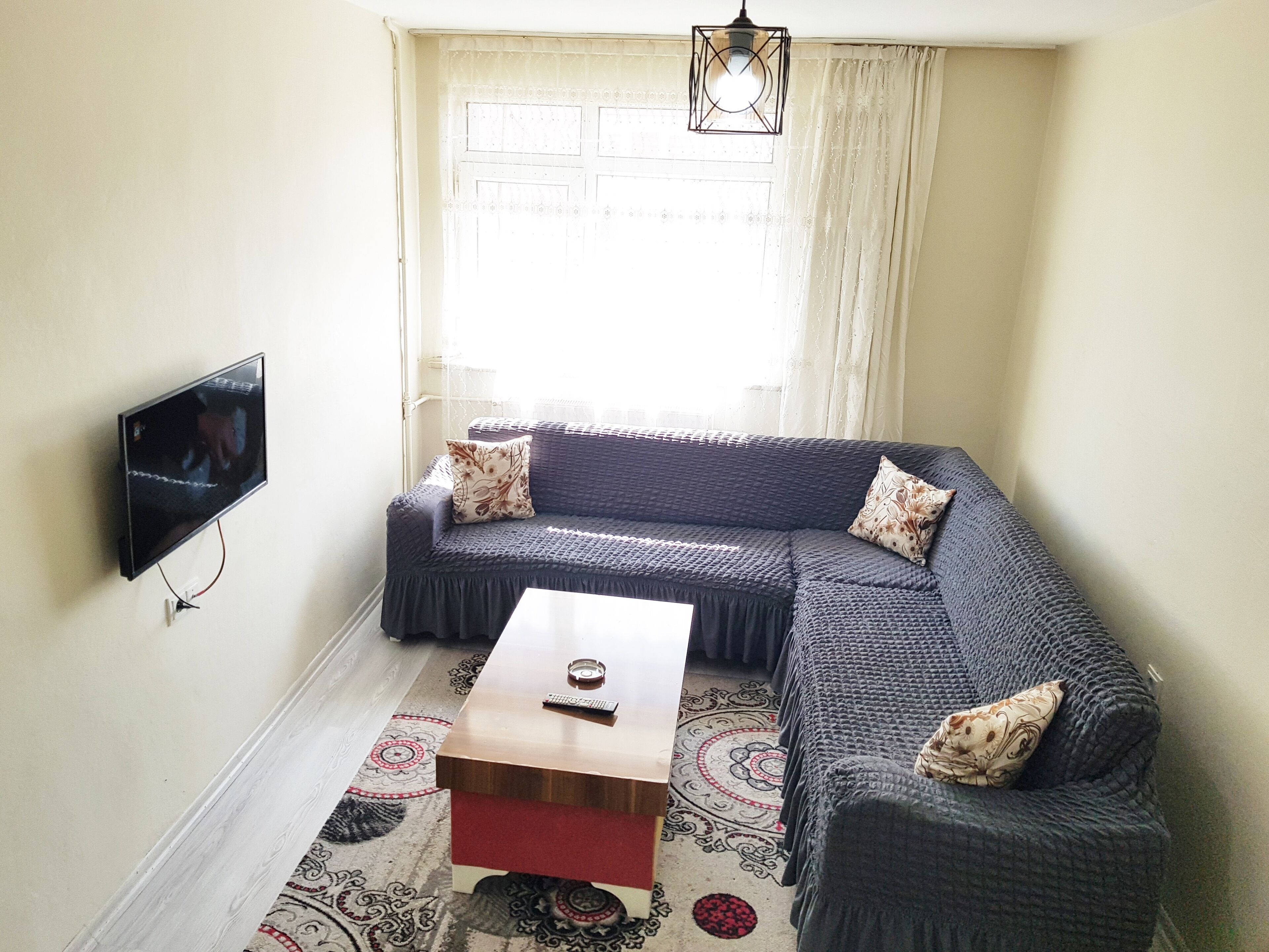 A living room with a sofa, a coffee table, and a TV mounted on the wall.