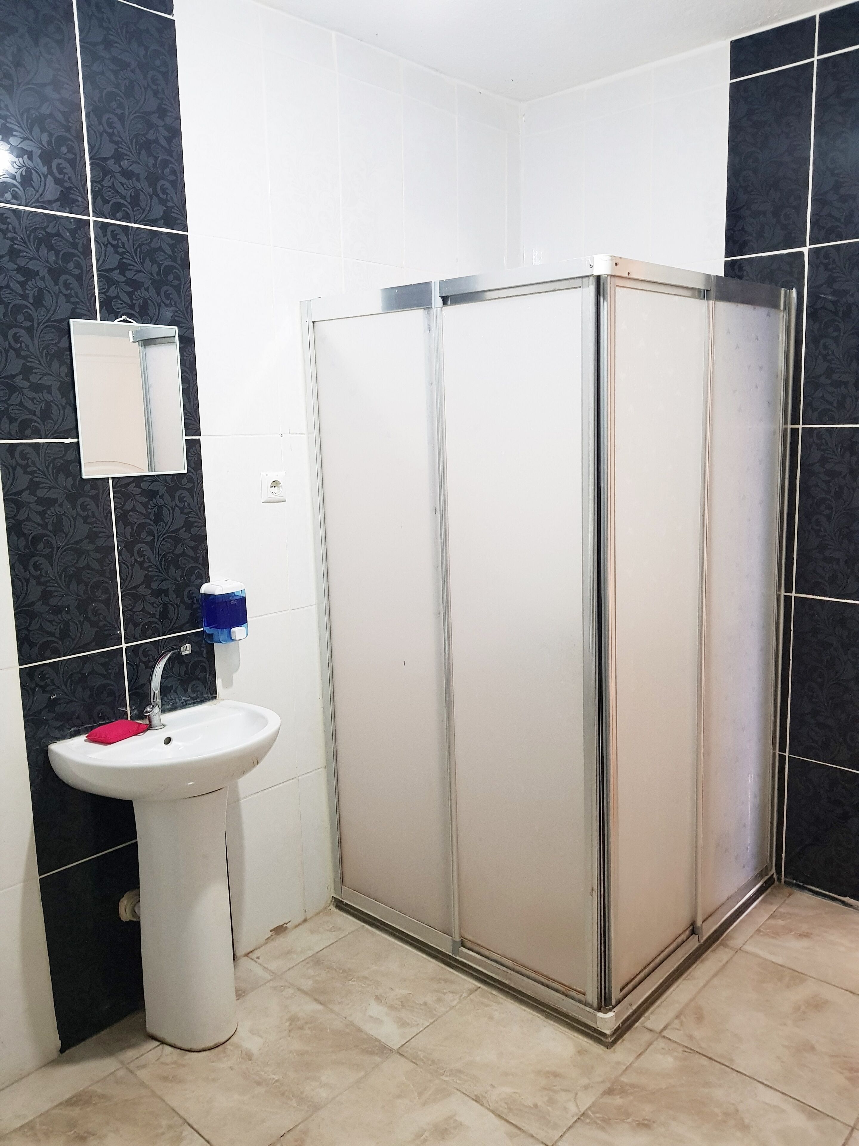 A bathroom with a white sink, a mirror, and a shower enclosure.