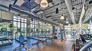 A gym with various exercise equipment, large windows, and a high ceiling.