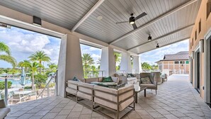 An outdoor covered patio with seating, a pool, and a view of the surrounding landscape.