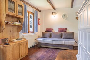 A cozy room with a wooden cabinet, a sofa with cushions, a radiator, and a wall clock. - Alpine Chalet Metka at Lake Bohinj (Bohinj)