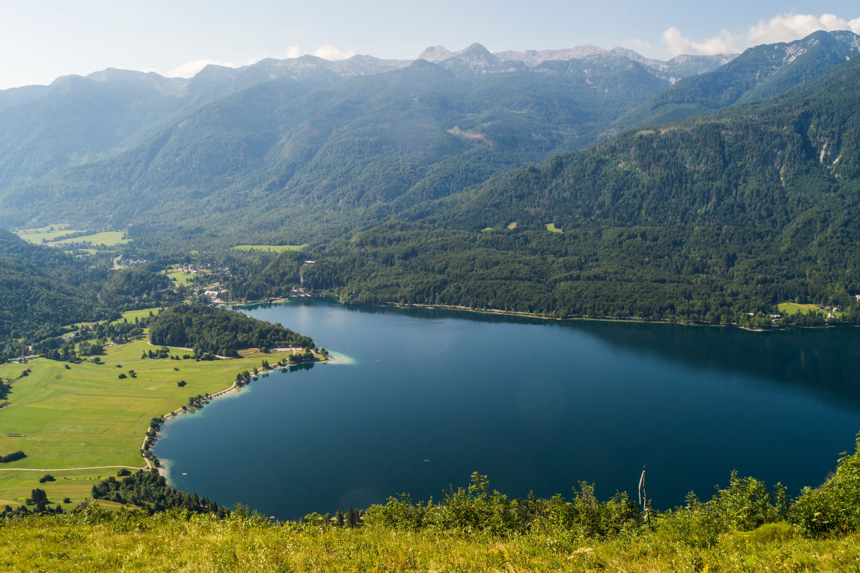 Une vue panoramique d’un lac entouré de collines et de montagnes verdoyantes.