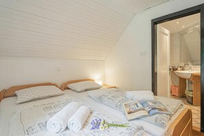 A bedroom with two beds, a bathroom with a sink, and a door leading to another room. - Alpine Chalet Metka at Lake Bohinj (Bohinj)