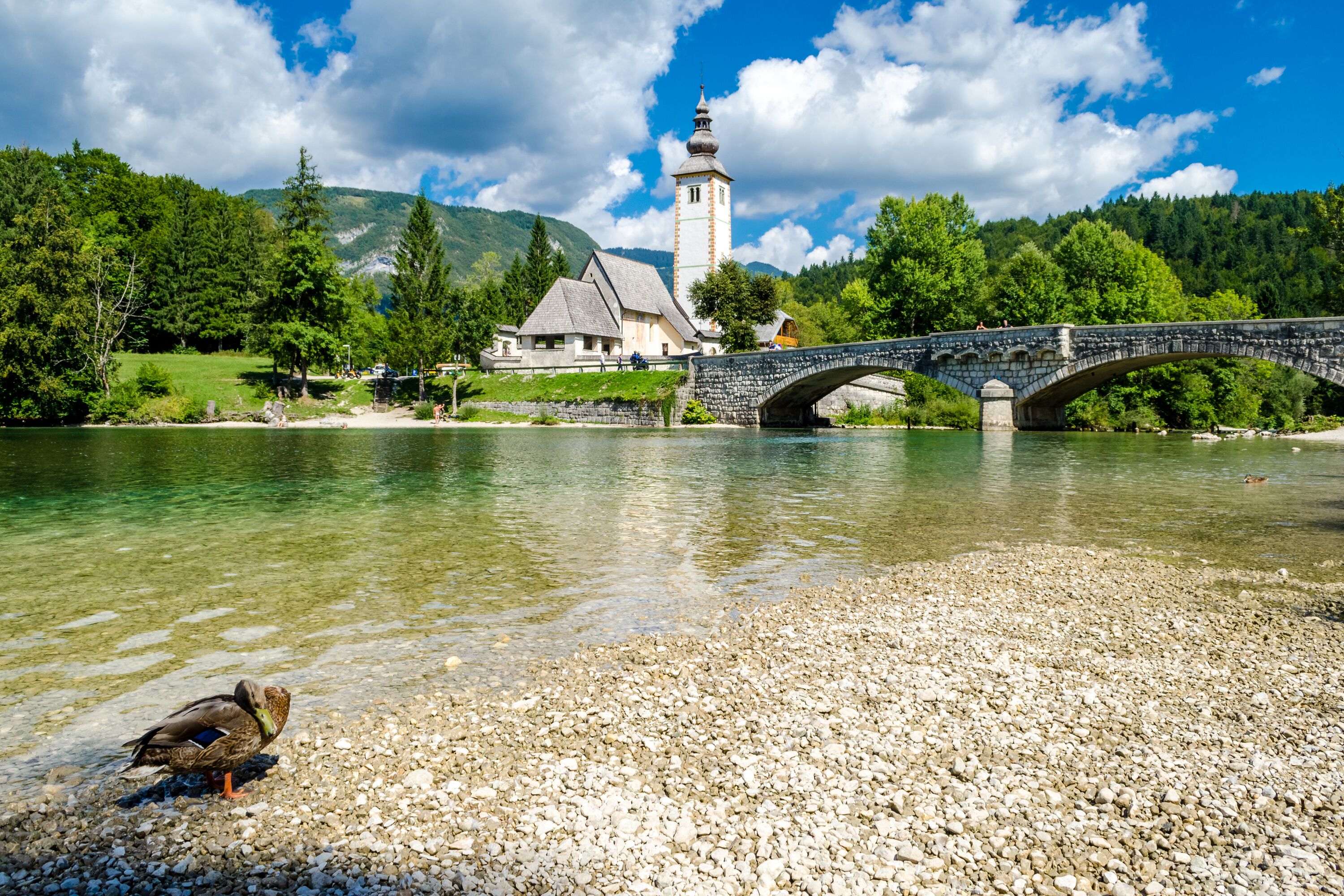 Un ponte di pietra che sovrasta un fiume, con una chiesa sullo sfondo.