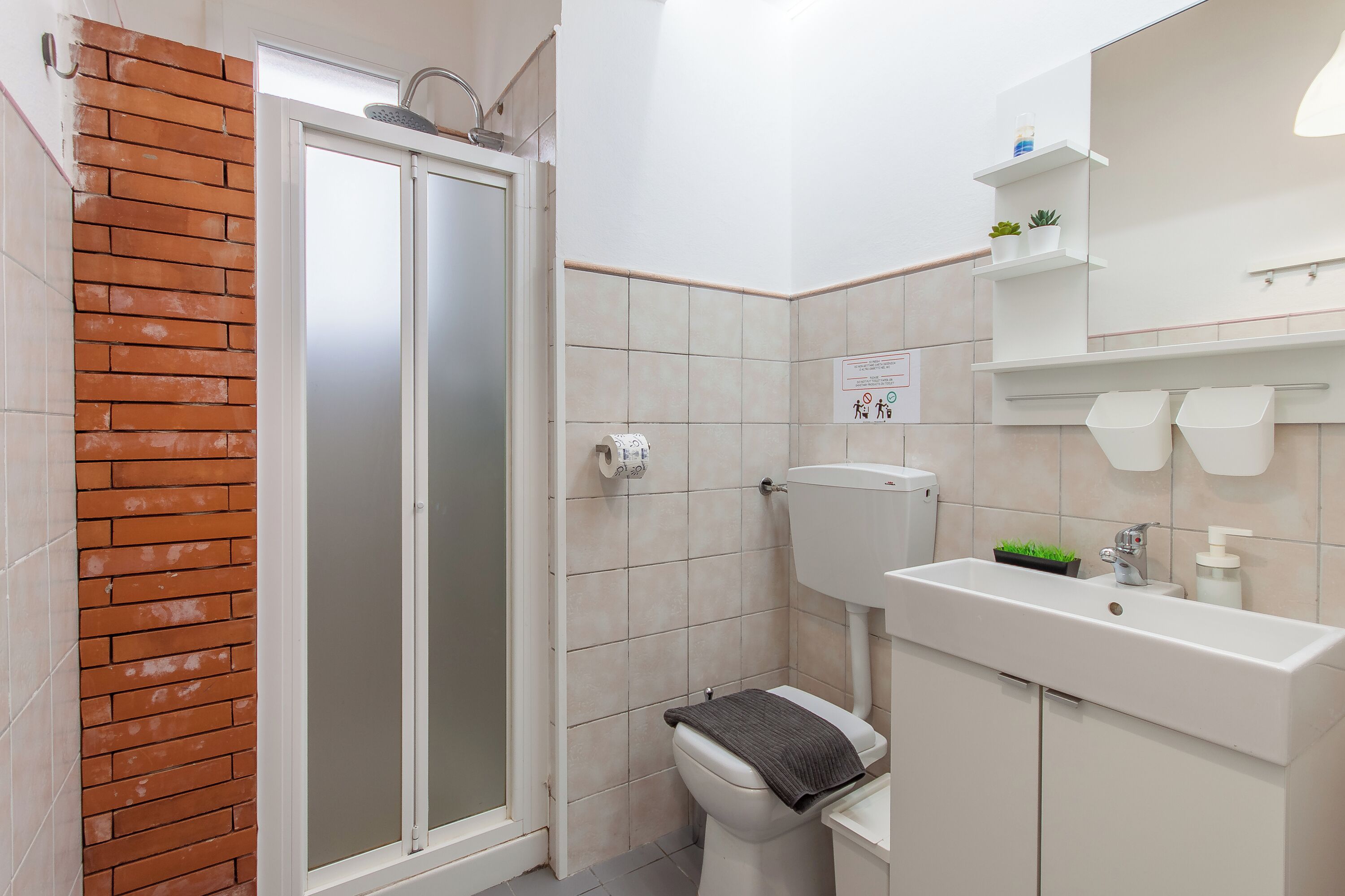 A bathroom with a shower, toilet, sink, and a mirror.