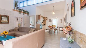 A spacious living area with a sofa, a dining table, and a kitchen in the background. - Alcamo Pool House (Alcamo)