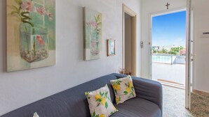 A living room with a grey sofa, two cushions with a lemon pattern, and three paintings on the wall. - Alcamo Pool House (Alcamo)