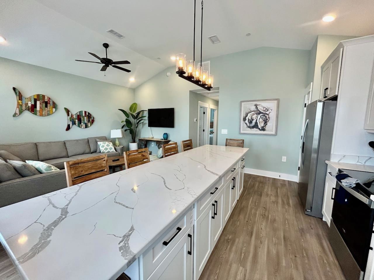 A modern kitchen with a marble countertop, wooden cabinets, and a ceiling fan.