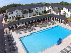 A swimming pool with lounge chairs and umbrellas, surrounded by multi-story buildings with balconies. - Relax on Island Time, 2 Bed Single Level Condo (Corolla)