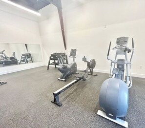 A gym with various exercise equipment including a rowing machine, an elliptical, and a stationary bike.