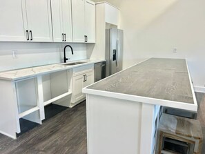 A kitchen with white cabinetry, a stainless steel refrigerator, and a wooden countertop.