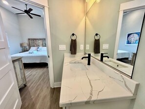 Ein Badezimmer mit weißer Marmorplatte, einem schwarzen Wasserhahn und einem Deckenventilator.