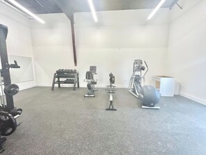 A gym with various exercise equipment including dumbbells, a bench press, a squat rack, and a stationary bike. - Relax on Island Time, 2 Bed Single Level Condo (Corolla)