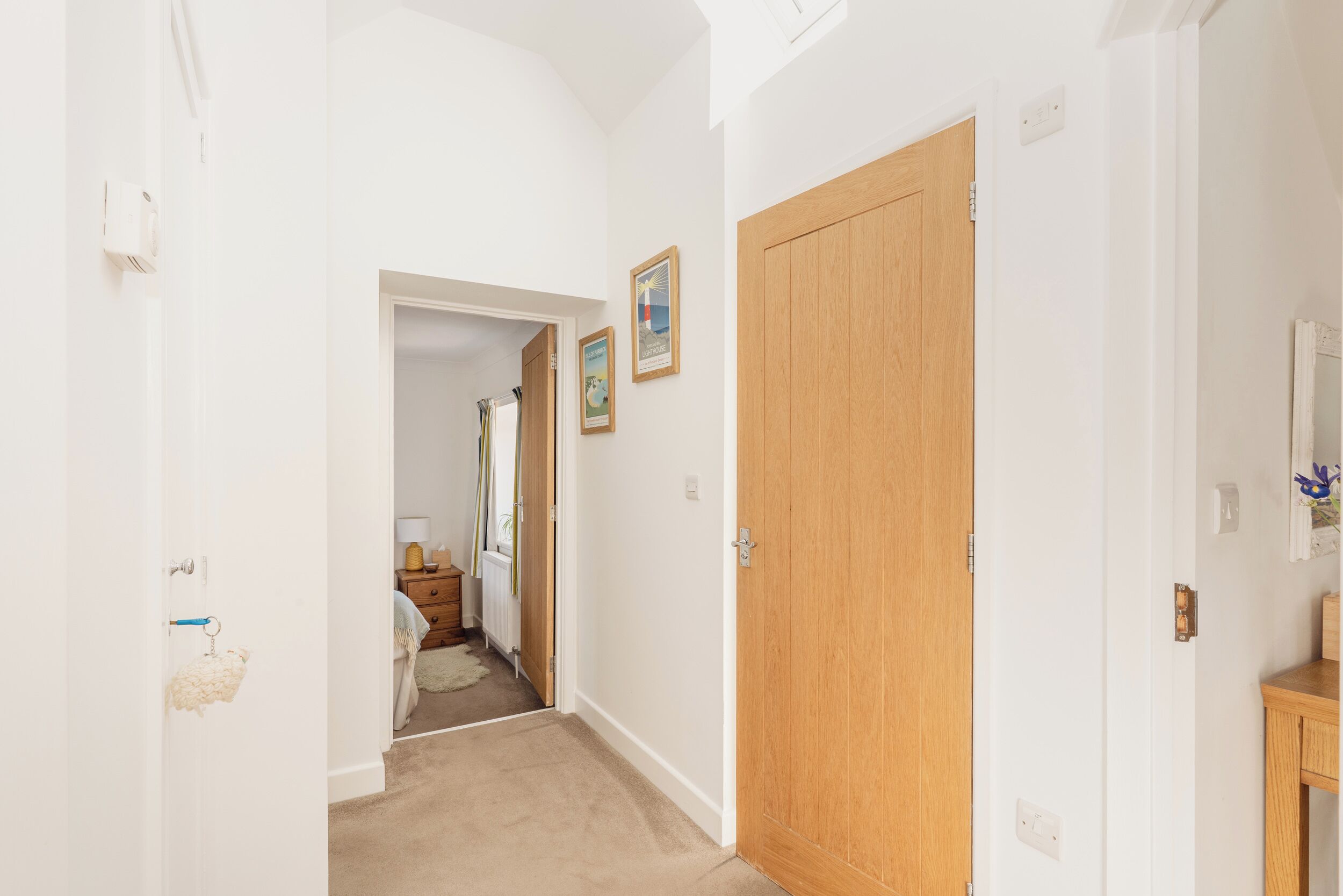 A hallway with a wooden door, white walls, and a carpeted floor.