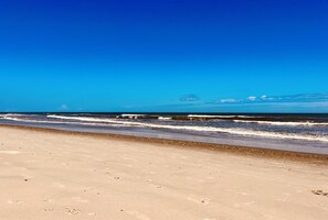 Enjoy a serene beach experience with calm ocean waves and soft sand.