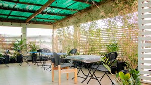 An outdoor patio with a table and chairs, surrounded by potted plants and a bamboo fence. - HG PALACE LODGE (Accra)