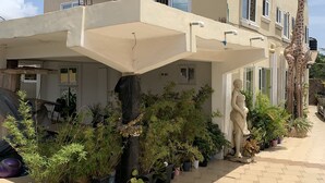 A building with a covered outdoor area, potted plants, and a statue. - HG PALACE LODGE (Accra)