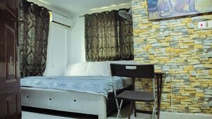 A bedroom with a bed, a chair, a stone wall, and a leopard painting. - HG PALACE LODGE (Accra)