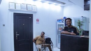 A reception area with a black door, a no smoking sign, and a refrigerator in the background. - HG PALACE LODGE (Accra)