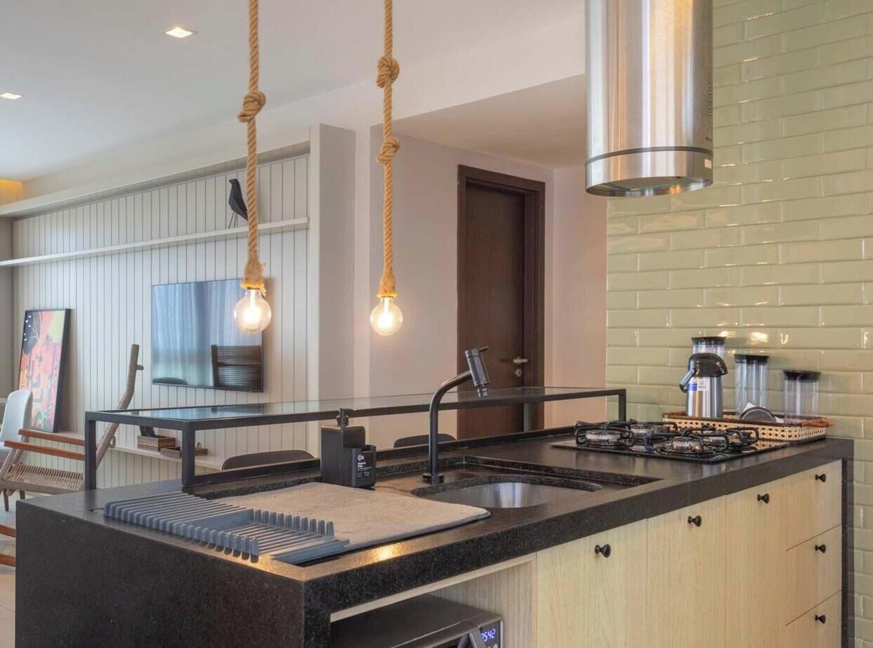 Una cocina moderna con una isla central, electrodomésticos de acero inoxidable e iluminación colgante.