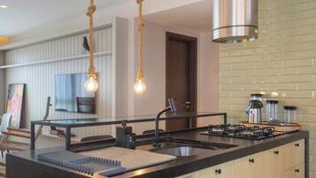 Una cocina moderna con una isla central, electrodomésticos de acero inoxidable e iluminación colgante.