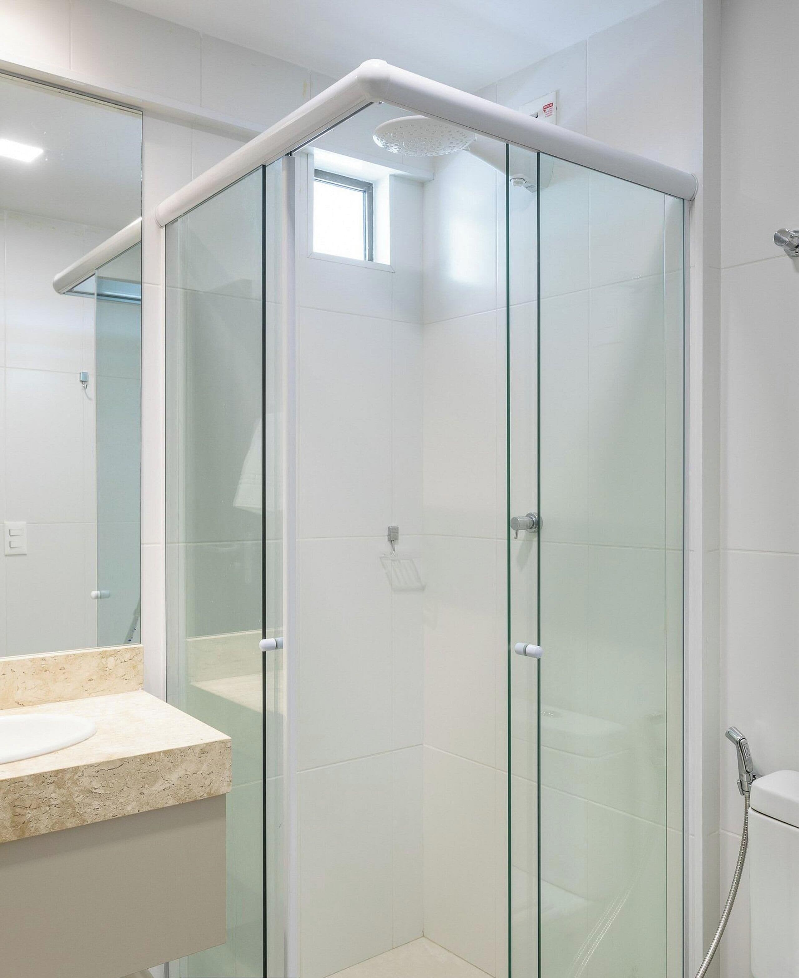 A modern bathroom with a glass-enclosed shower, a marble sink, and a large mirror.