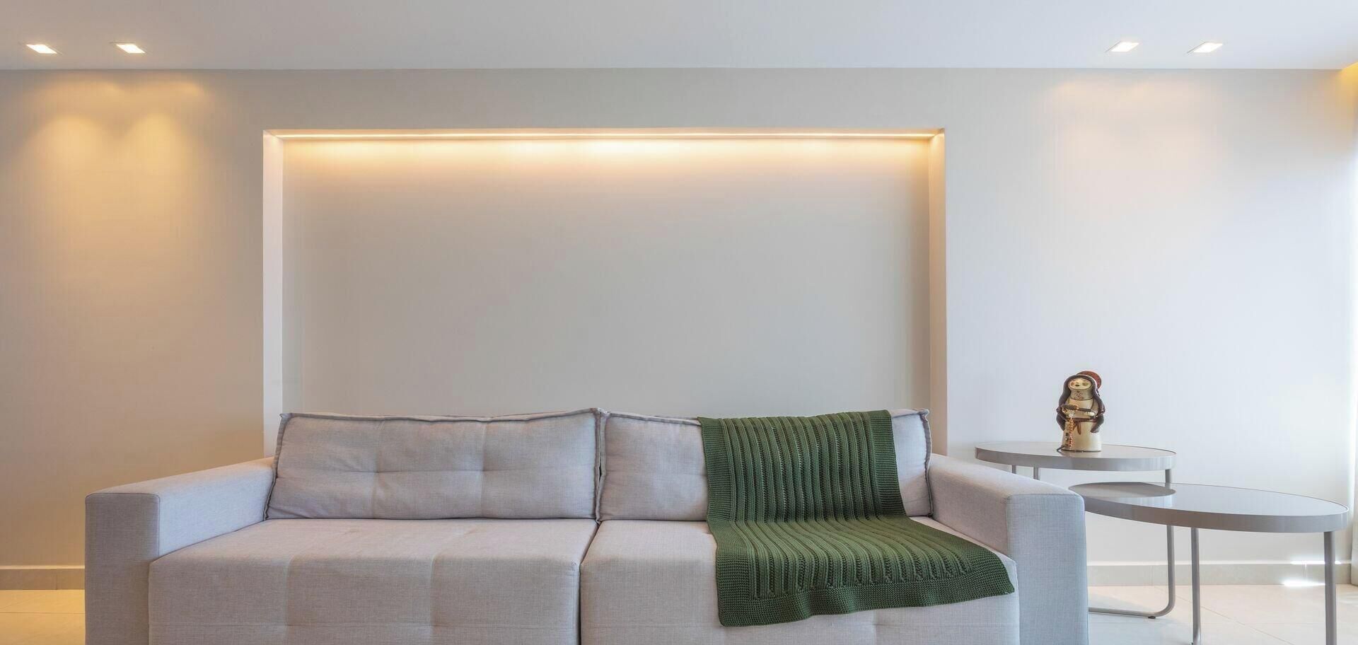 Un salon moderne avec un canapé, un plaid vert et une petite table ronde agrémentée d’un objet décoratif.