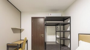 A compact room with a bed, a desk, and a built-in wardrobe with shelves. - Complexo Heron Marinho Flats (Campina Grande)
