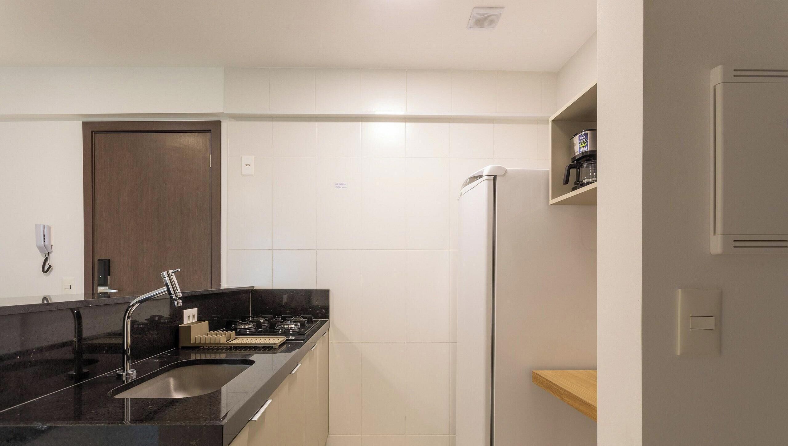 A modern kitchen with a black countertop, stainless steel faucet, and a built-in oven.