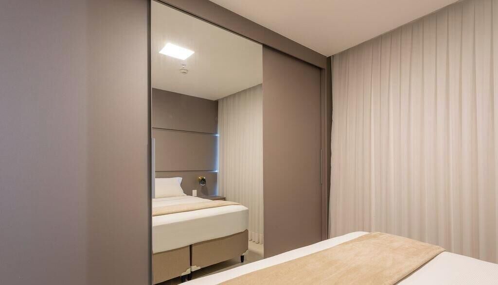 Een slaapkamer met een bed, nachtkastje en spiegel.